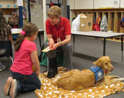 A Paws for Tales Volunteer and her therapy dog talk about a book with a student